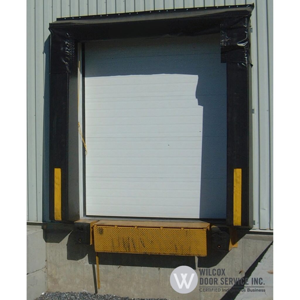 Mechanical dock leveler below a sectional loading door