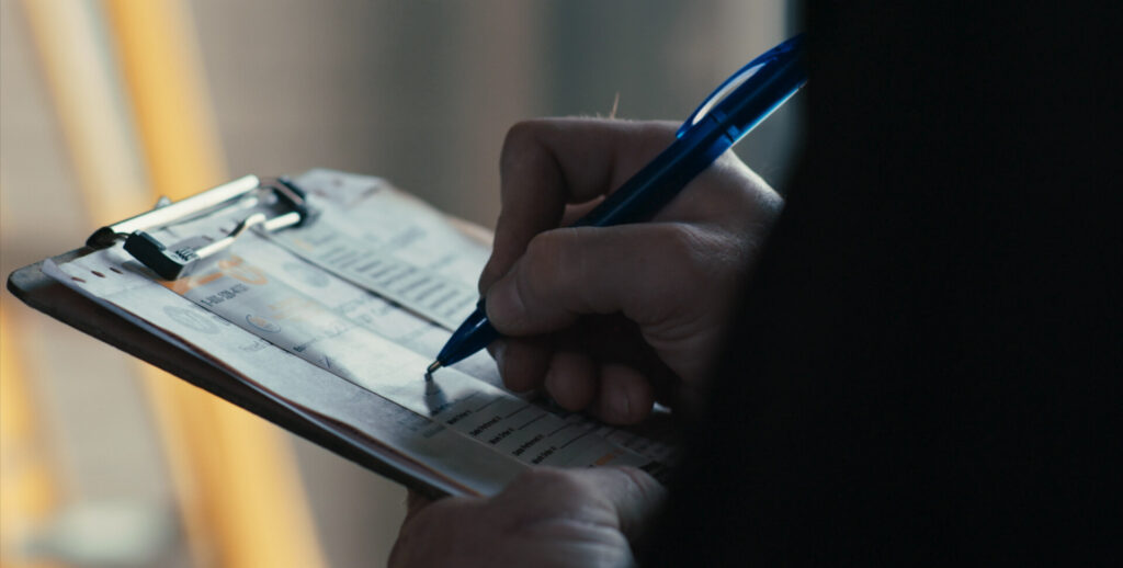 Close-up of worker writing on a clipboard during a maintenance check