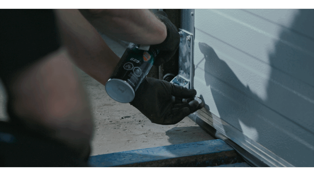 Technician working on an overhead door with a power tool