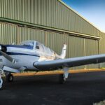 Small airplane parked outside an aircraft hangar