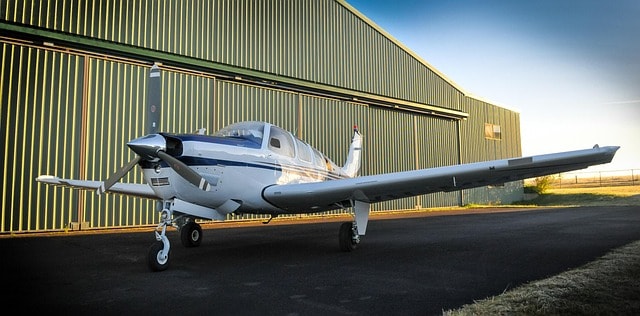 Small airplane parked outside an aircraft hangar